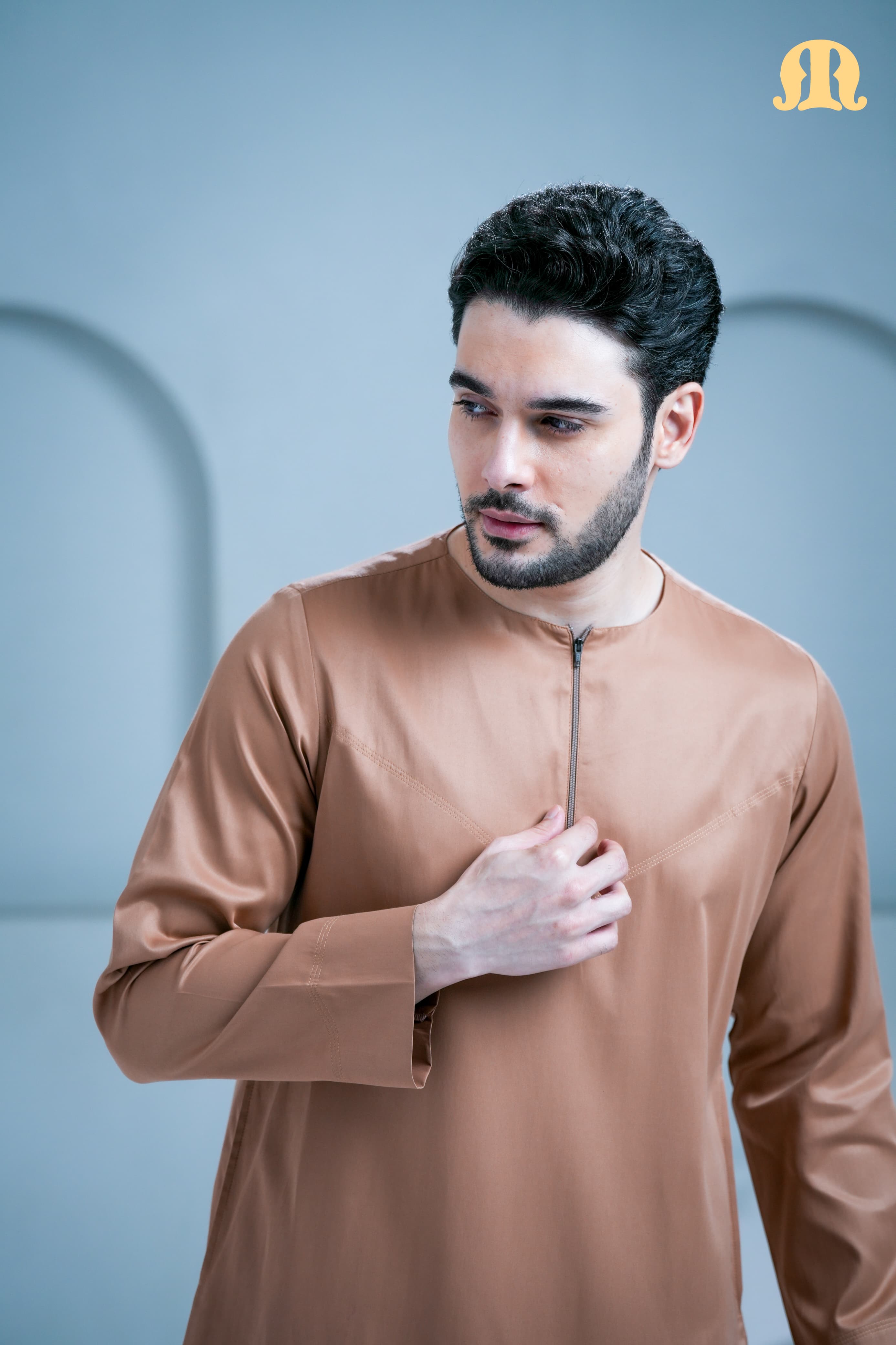 Man wearing a brown long-sleeve shirt against a light blue background